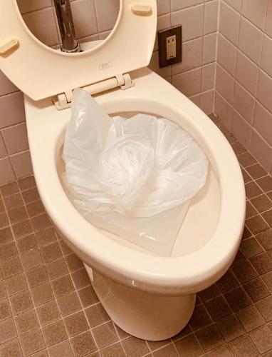 トイレの便器の中に水の入ったビニール袋を落とし込んでいる写真